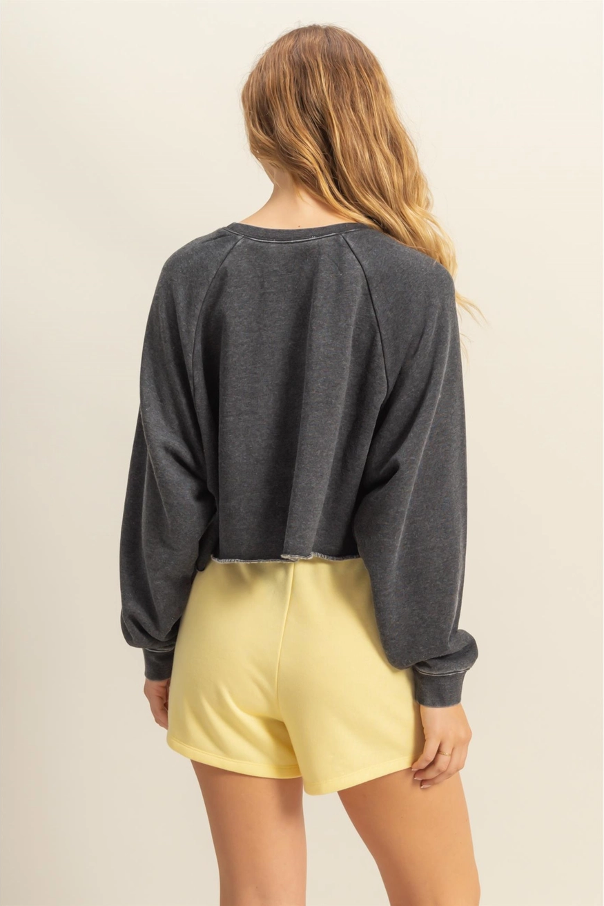 Person wearing a dark gray sweatshirt and yellow shorts on a beige background