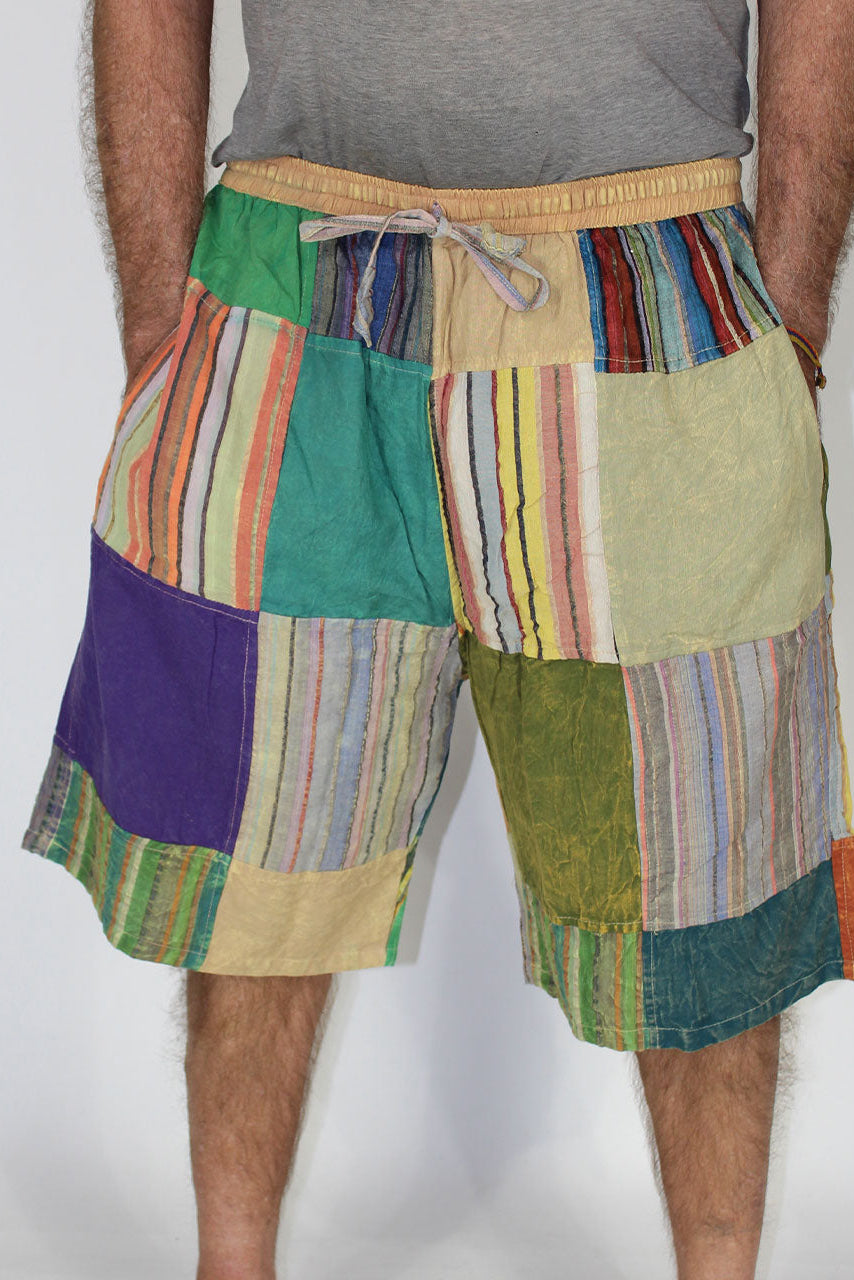Colorful patchwork shorts worn by a person on a plain background