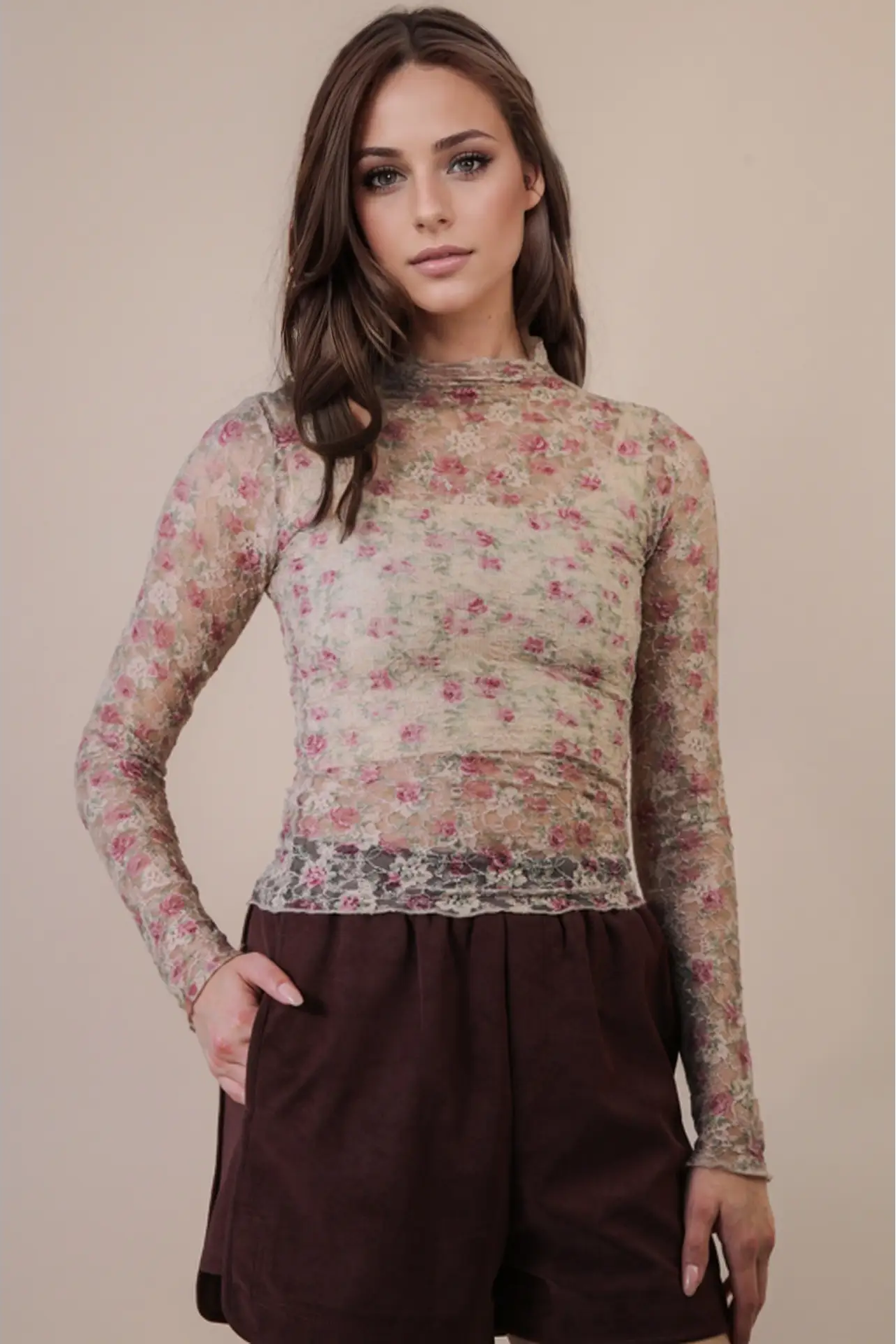 Woman wearing a floral long-sleeve top and brown pants against a beige background