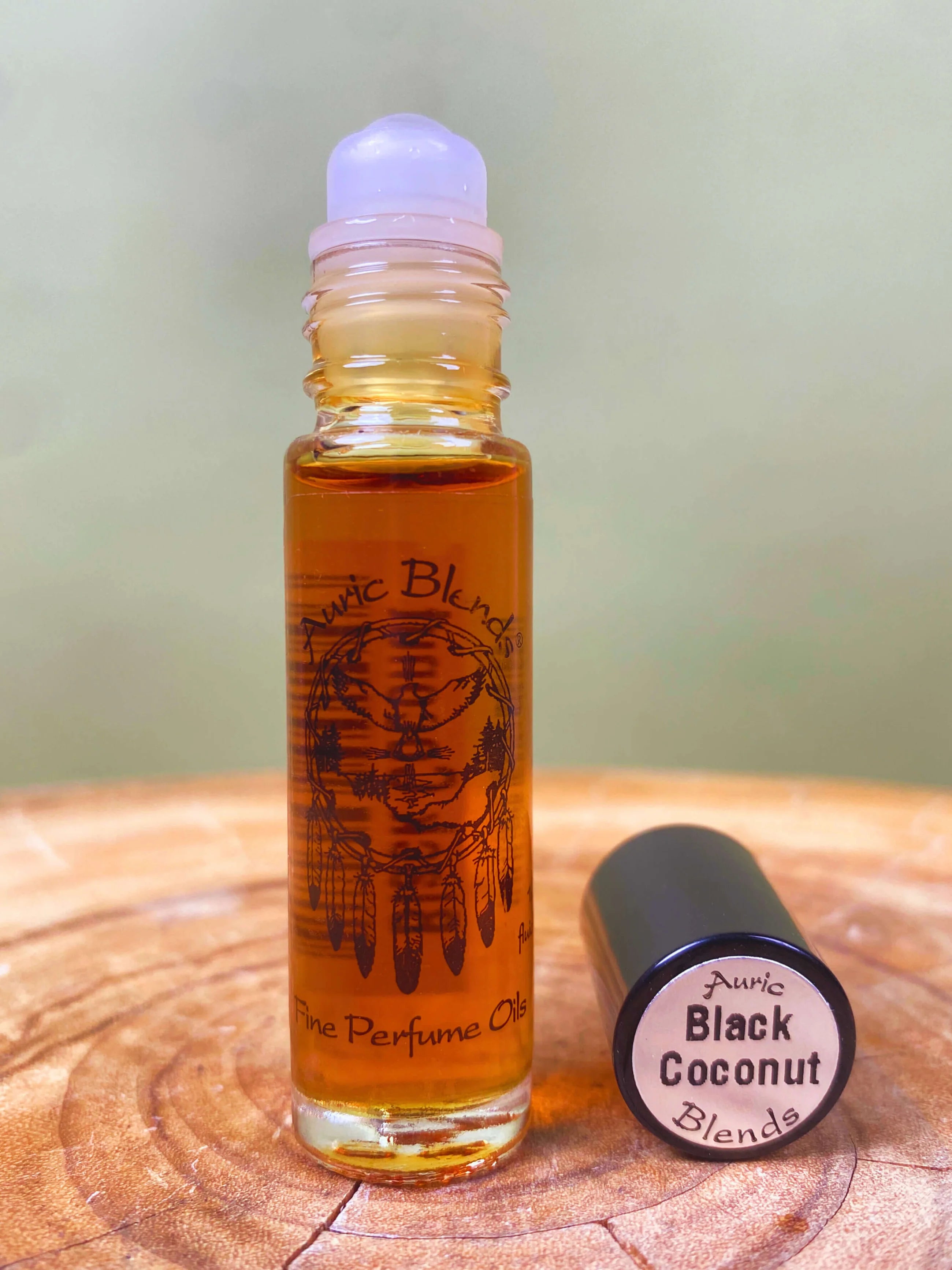 Roll-on bottle of Auric Blends Black Coconut perfume on a wooden surface with a blurred background