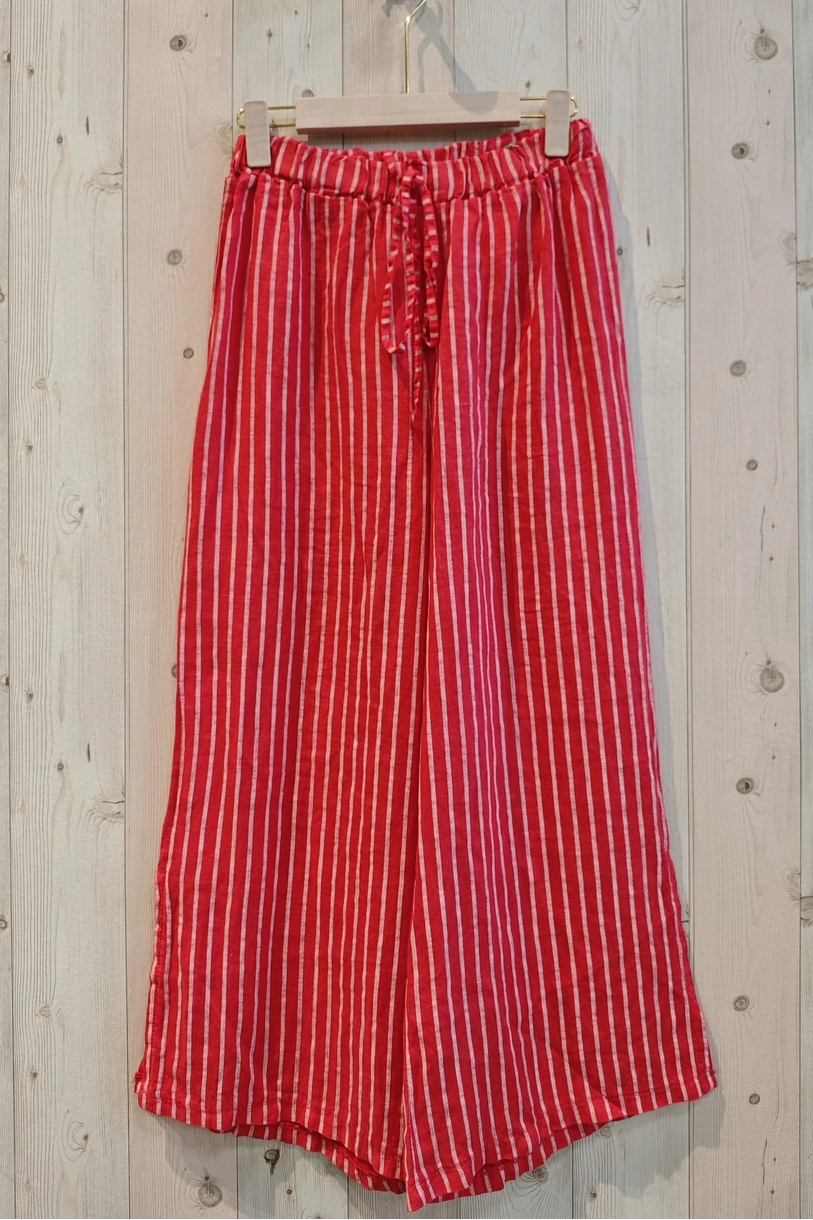 Red and white striped pants hanging on a wooden wall.