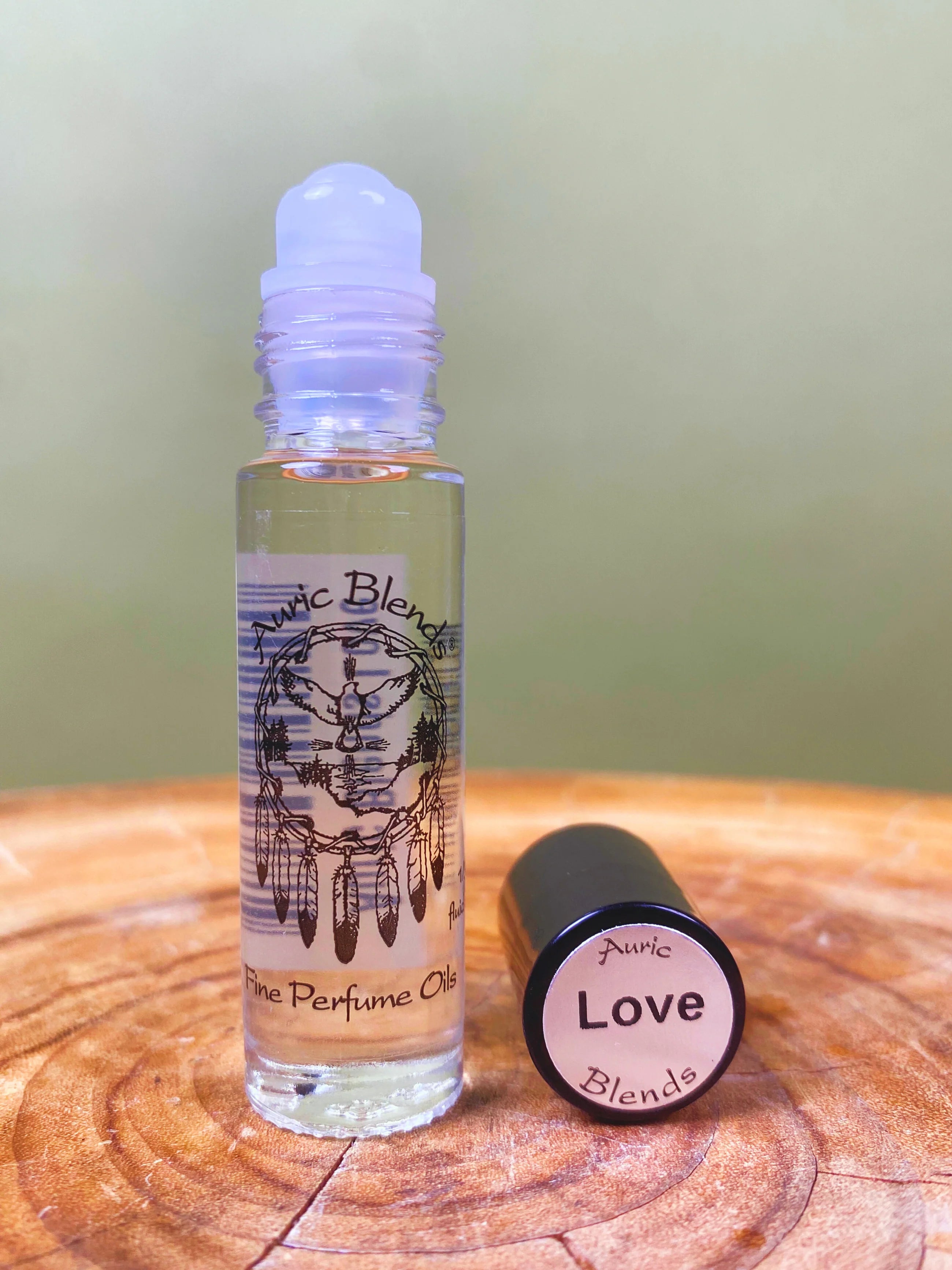Roll-on bottle of Puric Perfume Oils with a cap labeled 'Love Blends' on a wooden surface.