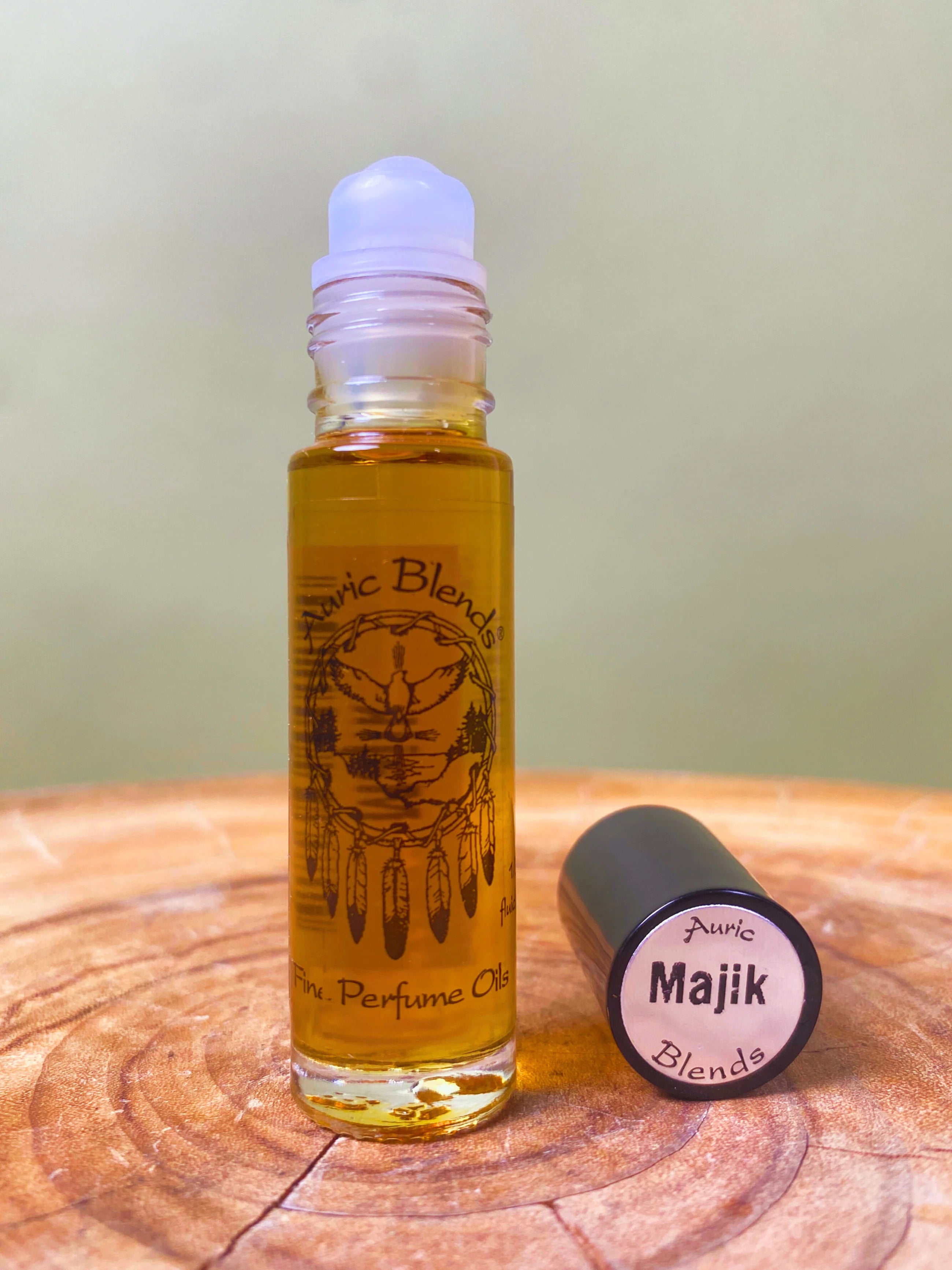 Roll-on bottle of Auric Blends perfume oil on a wooden surface with a blurred background