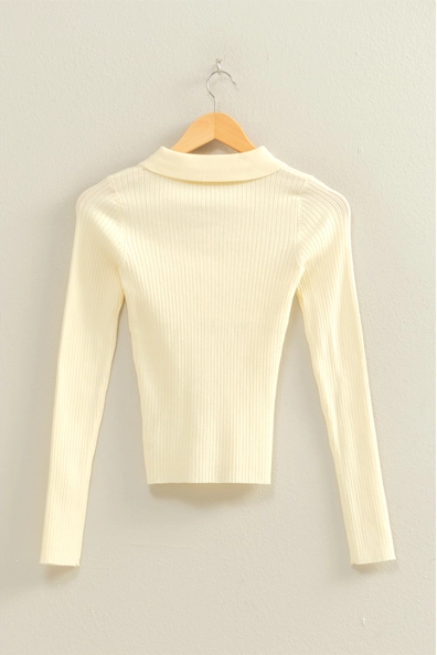 Cream-colored ribbed sweater on a wooden hanger against a light gray background