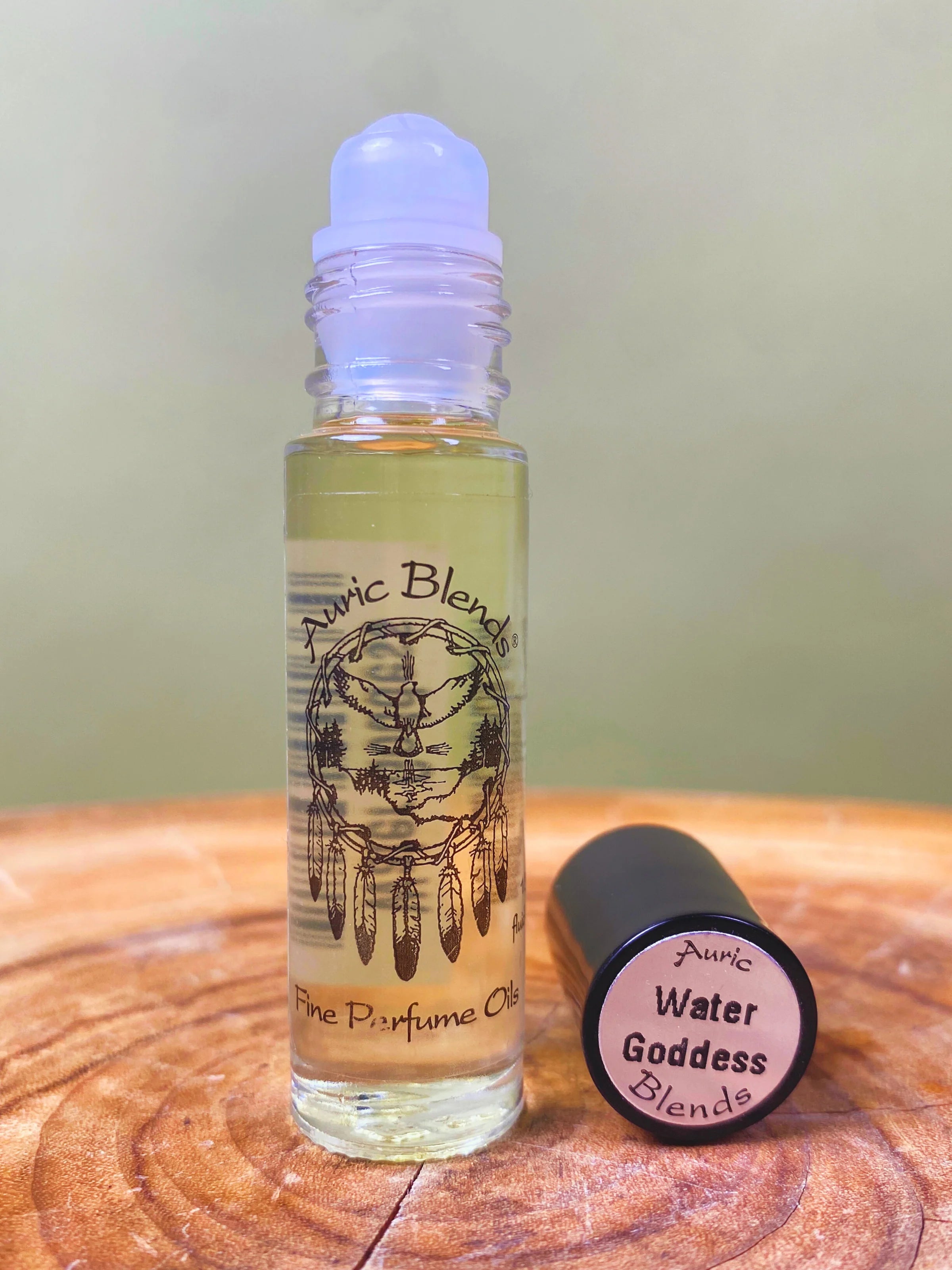 Roll-on bottle of Auric Blends perfume oil on a wooden surface with a green background